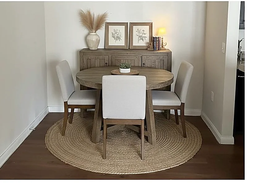 Dining area with round table, upholstered chairs, and framed botanical art
