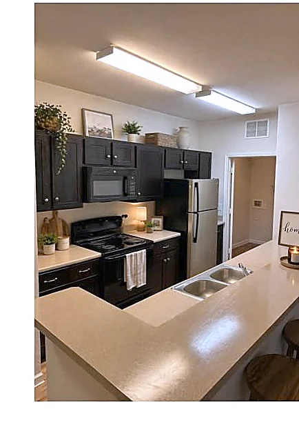 Modern kitchen with dark cabinetry, breakfast bar, and black appliances